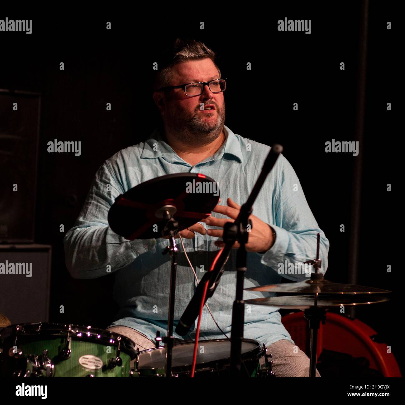 Tom Bancroftmaking eine Ankündigung bei einem Gig seiner Band 'in Common' im Herts Jazz Club in St. Albans Stockfoto