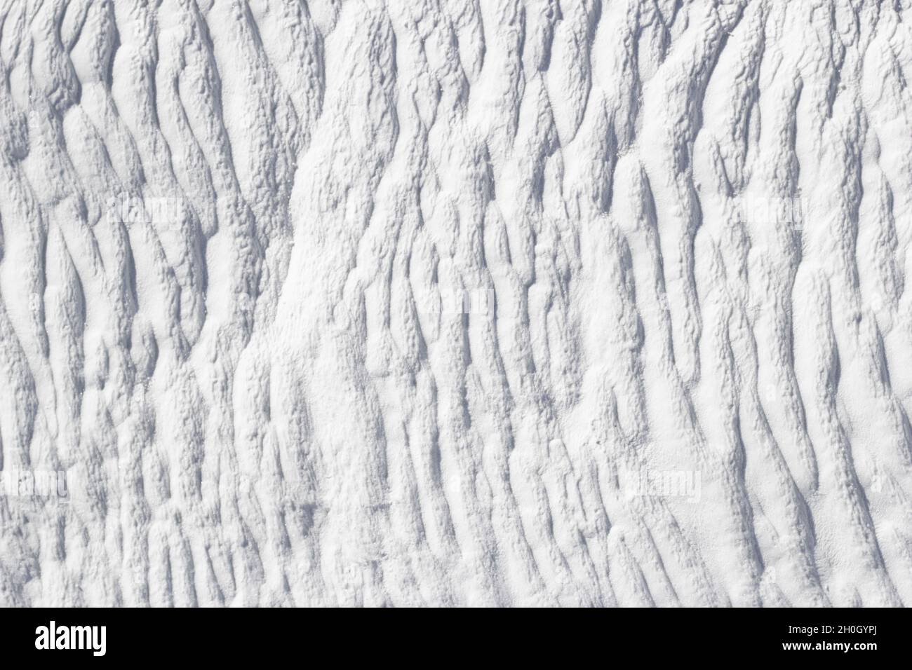 Weiße Textur von Pamukkale Calciumtravertin in der Türkei, Muster von vertikalen Linien, Nahaufnahme. Stockfoto