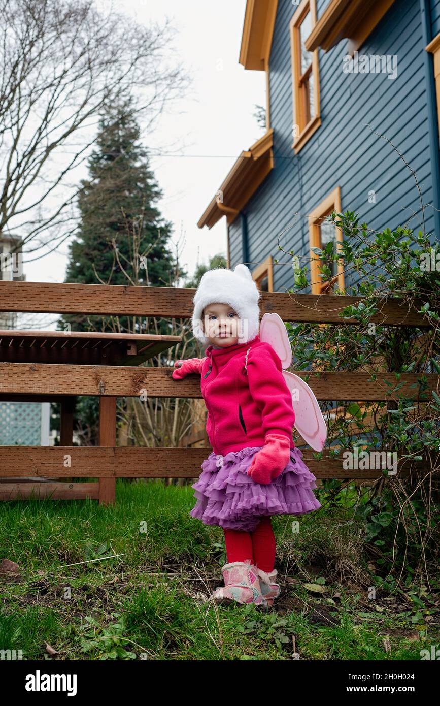 Ein kleines Mädchen, das sich dazu entschieden hat, ihre Feenflügel als ihr tägliches Outfit zu hören. Stockfoto