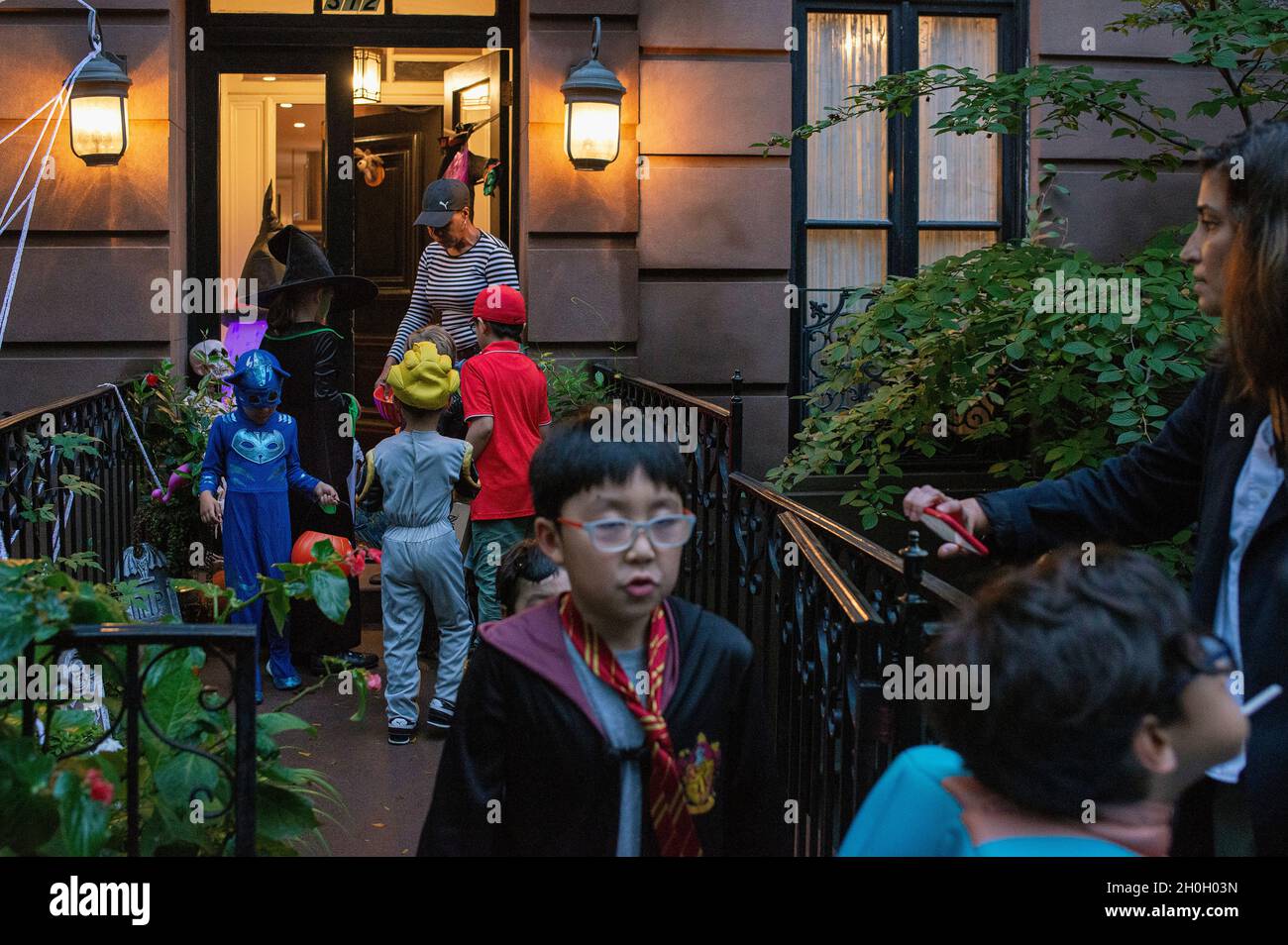 Eine Frau, die an Halloween in New York City Süßigkeiten an Trick or Treators ausgibt. Stockfoto