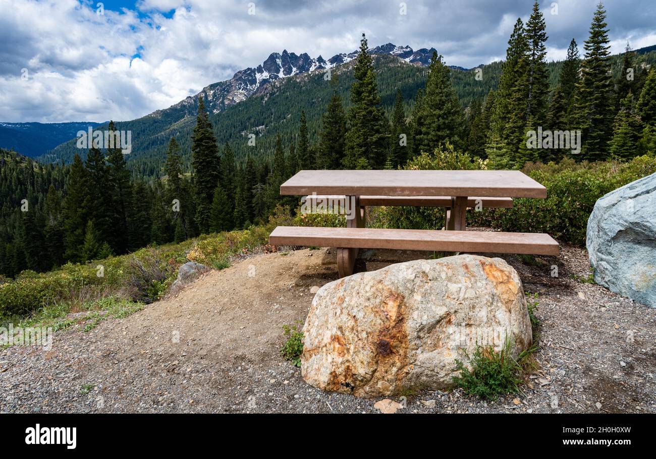 Foto eines Picknicktisches mit Felsbrocken und Blick auf die Sierra Buttes in den Bergen der Sierra Nevada im Hintergrund. Stockfoto