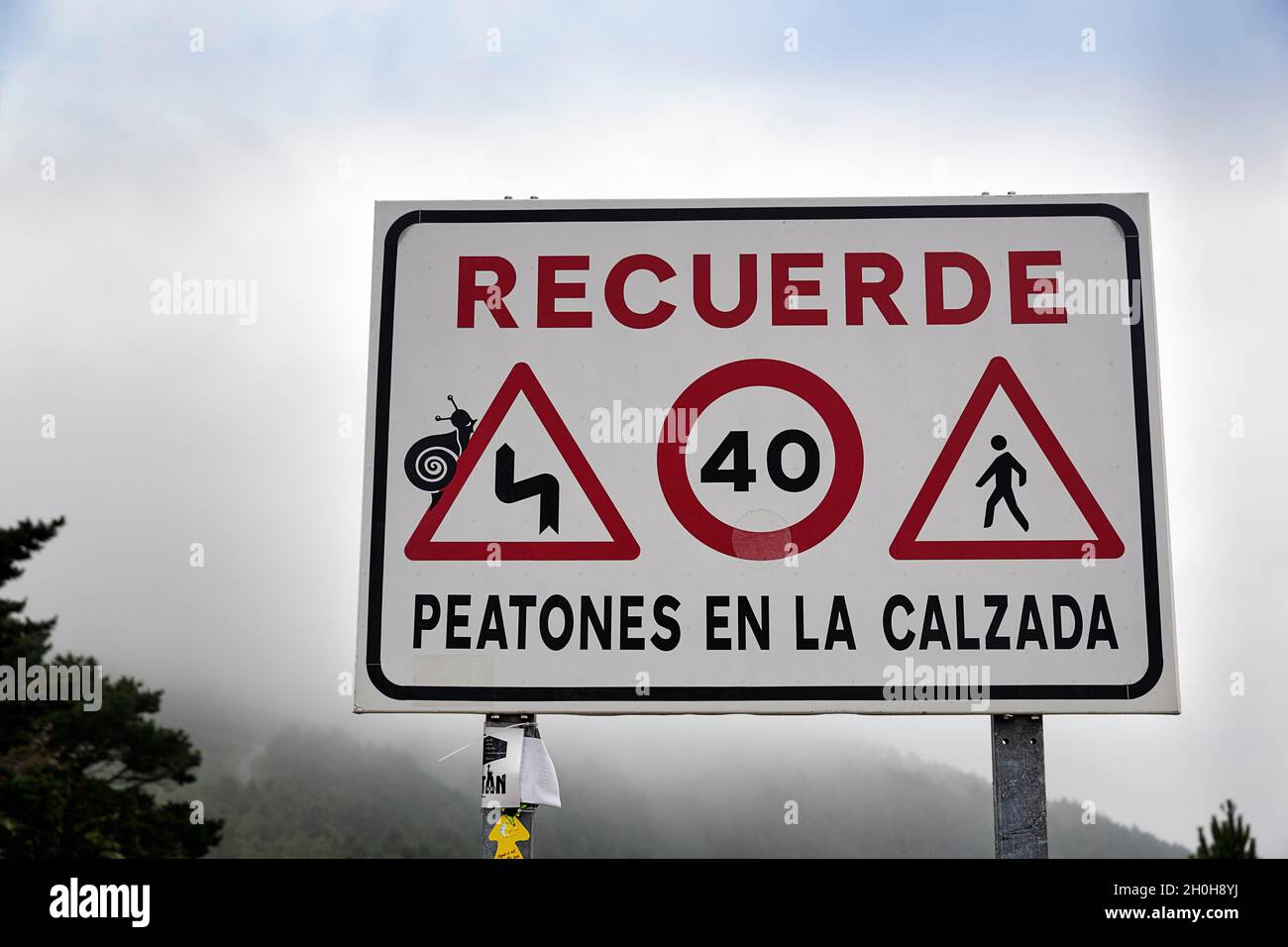 Schild mit verschiedenen Verkehrsschildern, die Fußgänger auf der Straße warnen, neblige Berglandschaft, Jakobsweg am Kap Finisterre, Einer Provinz von Coruna Stockfoto