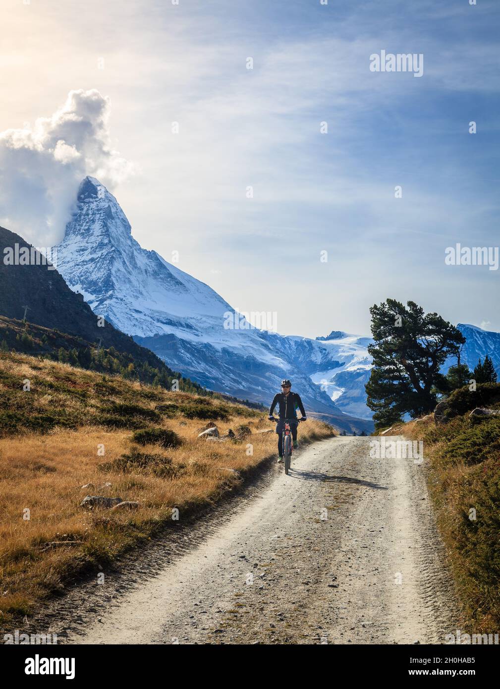 Zermatt, Schweiz, 26. September 2015: Ein Radfahrer auf einer Schotterstraße in den Schweizer Alpen mit Matterhorn im Hintergrund Stockfoto
