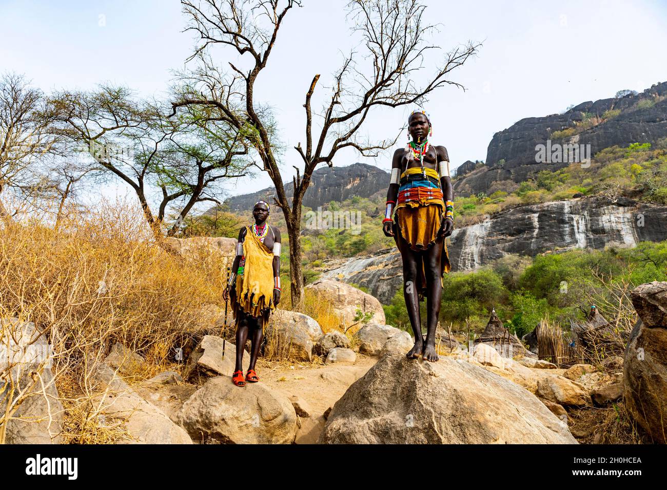 Traditionell gekleidete junge Mädchen aus dem Stamm der Laarim stehen auf einem Felsen, Boya Hills, Eastern Equatoria, Südsudan Stockfoto