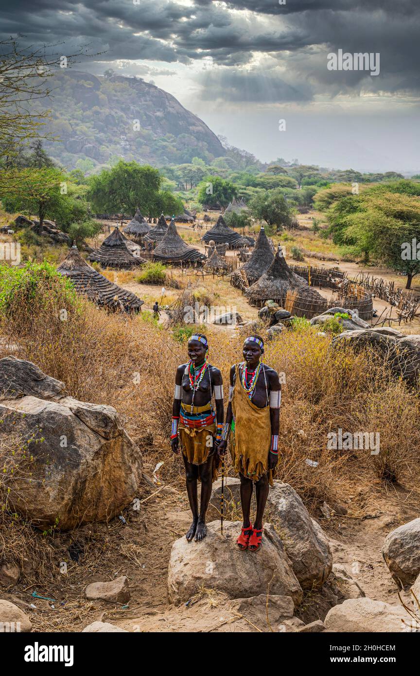 Traditionell gekleidete junge Mädchen aus dem Stamm der Laarim stehen auf einem Felsen, Boya Hills, Eastern Equatoria, Südsudan Stockfoto
