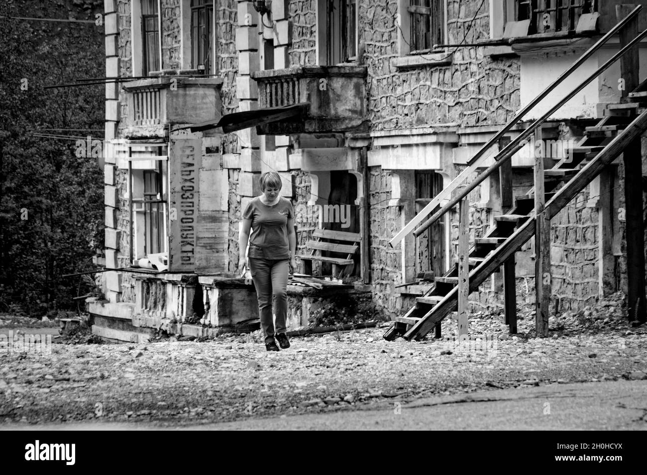 SADON, RUSSLAND - 07 25 2021: Einsamer Fremder zögert, auf verwüsttem Territorium neben alten verlassenen teilweise eingestürzten Gebäuden weiter zu schreiten Stockfoto
