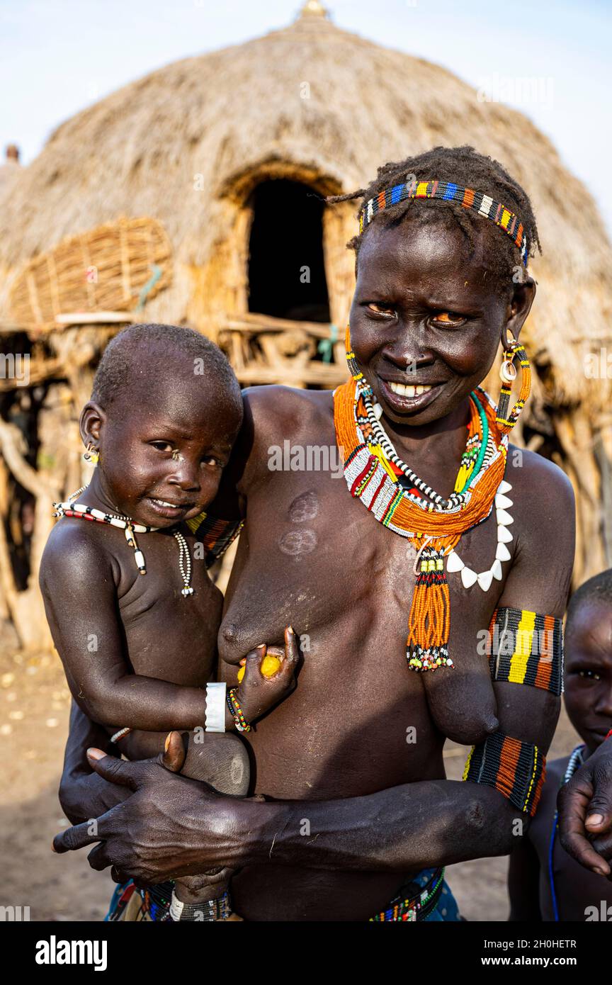 Frauen mit ihren Kindern des Jiye-Stammes vor ihren Hütten, Eastern Equatoria State, Südsudan Stockfoto
