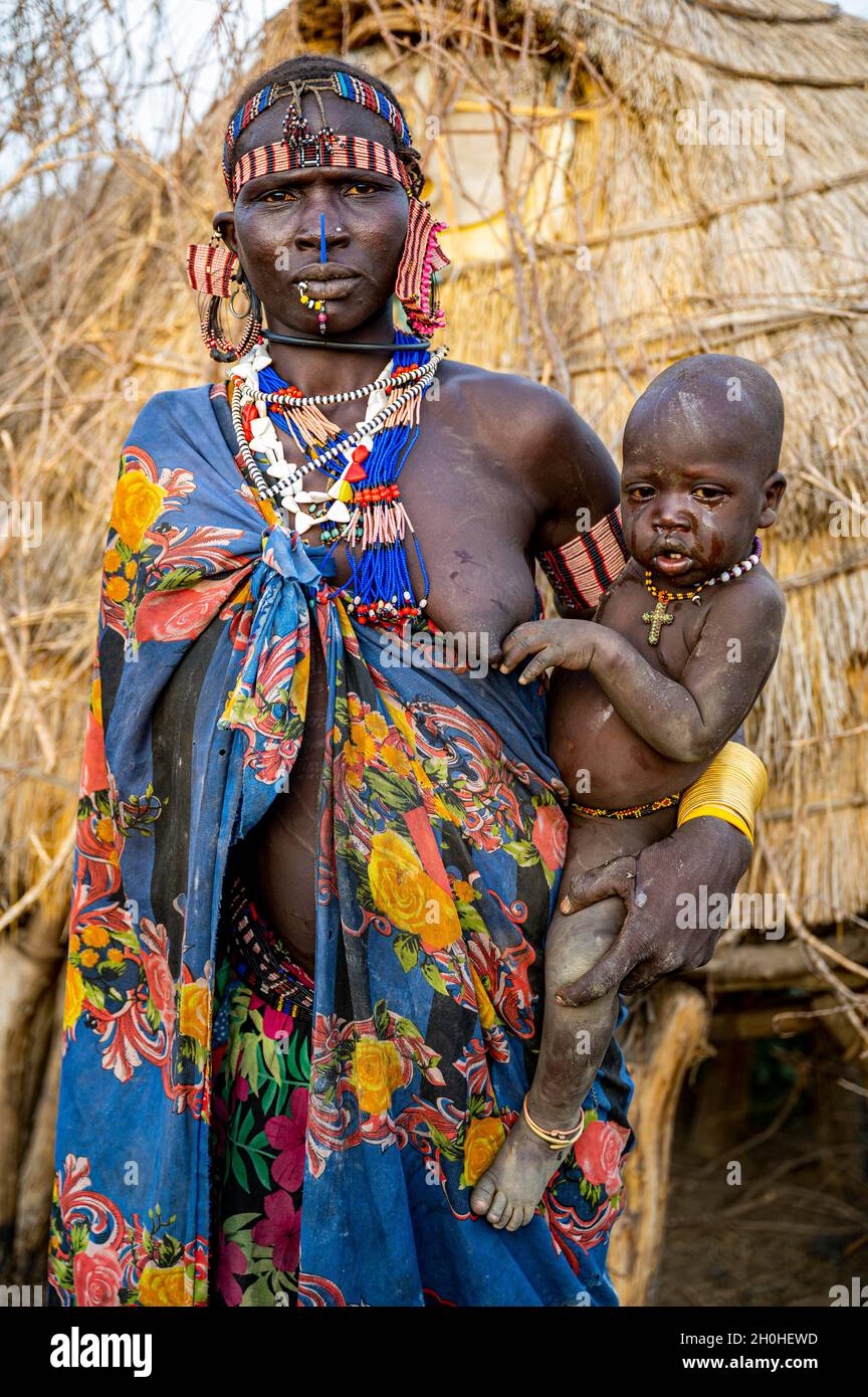 Frau mit ihrem Kind vor ihrer Hütte, Jiye-Stamm, Eastern Equatoria State, Südsudan Stockfoto
