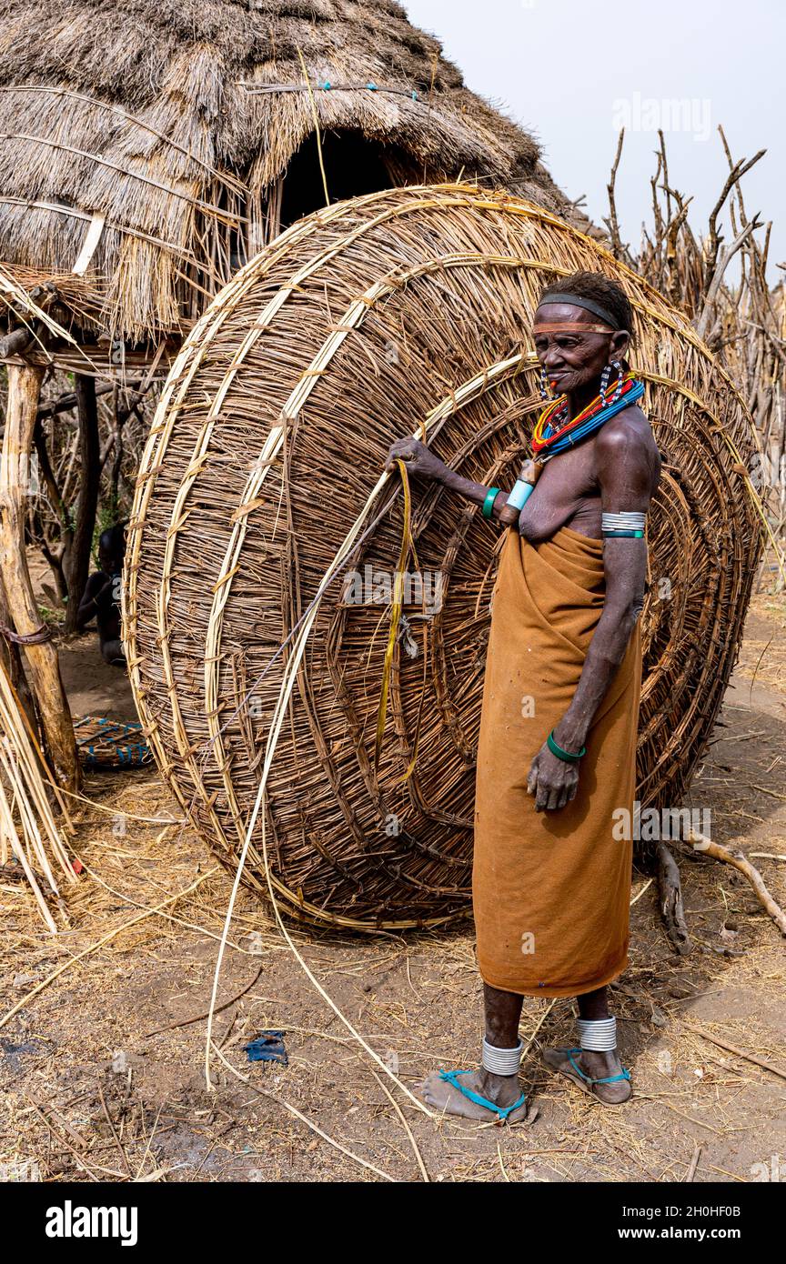Frau vor ihrer Hütte mit vorbereitetem Schilf, Jiye-Stamm, Staat Eastern Equatoria, Südsudan Stockfoto