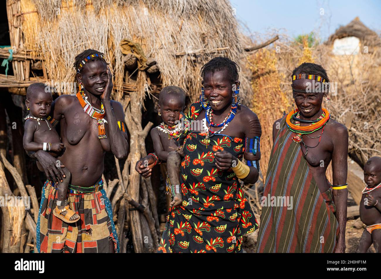 Frauen mit ihren Kindern des Jiye-Stammes vor ihren Hütten, Eastern Equatoria State, Südsudan Stockfoto