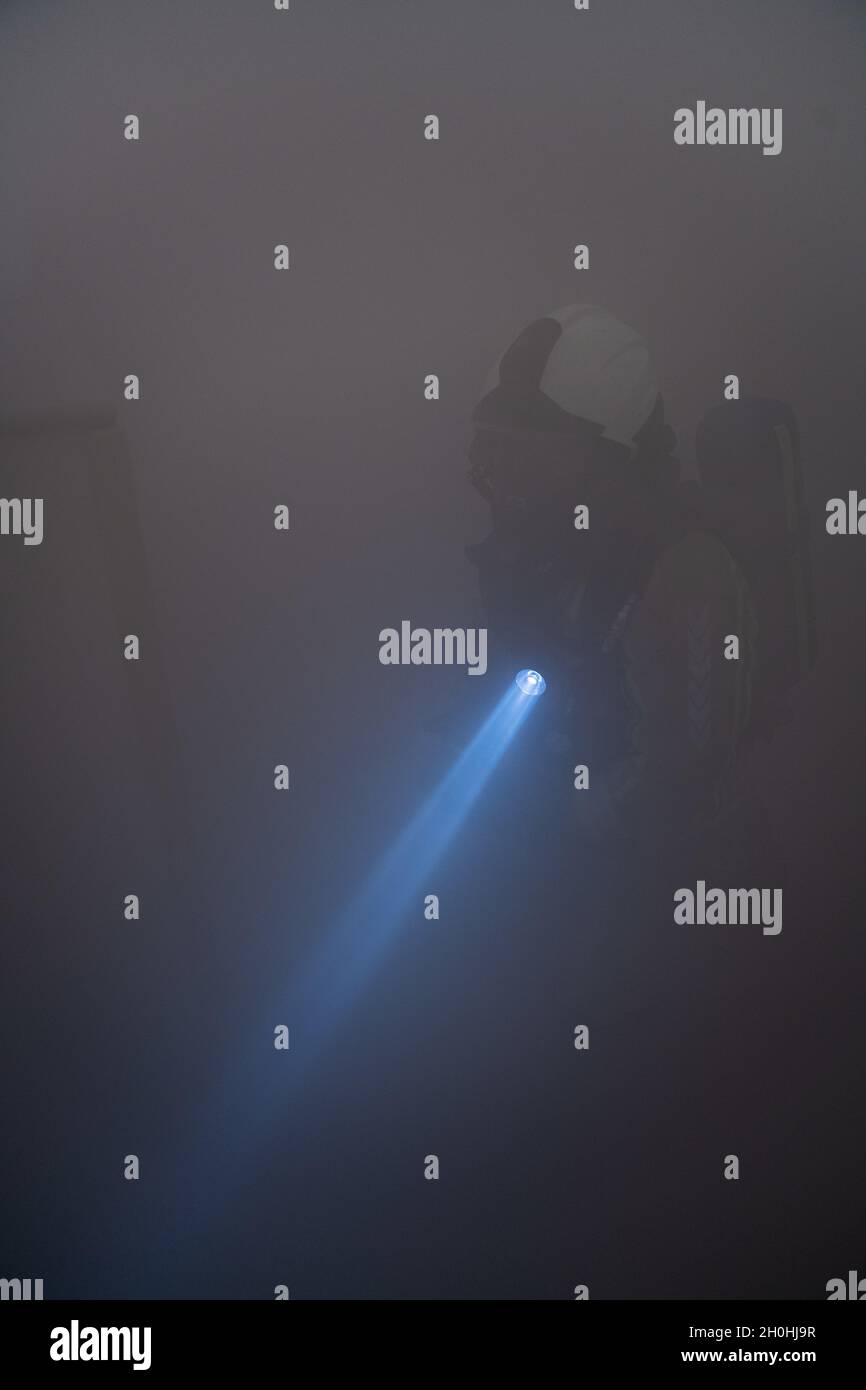 Ein belgischer Feuerwehrmann mit Supreme Headquarters Allied Powers Europe Fire Protection Services sucht während einer Feuerübung in FORM in Mons, Belgien, am 22. September 2021 in einem geräucherten, gefüllten Raum nach einem simulierten Opfer. Das USAG Benelux Fire Prevention Office leitete die Brandübung für die kommende Fire Prevention Week. (USA Foto der Armee von Pierre-Etienne Courtejoie) Stockfoto