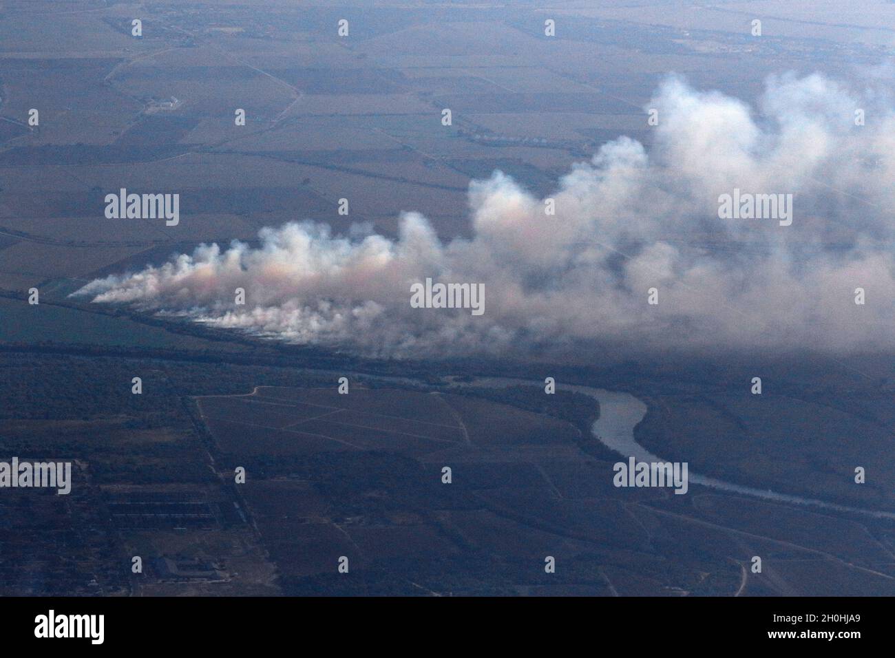 Ein Feuer brennt in der Ferne entlang des Rio Grande River und erzeugt einen Dunst über dem Himmel, als ein Hubschrauber der texanischen Nationalgarde, Joint Counterdrog Task Force LUH-72, „Lakota“, das Gebiet nach vermuteten Drogenhändlern durchsucht. Das Texas Counterdrog-Programm unterstützt die Strafverfolgungsbehörden entlang der Grenze zwischen Texas und Mexiko seit mehr als 30 Jahren bei der Erkennung, Abschreckung und dem Verbot von Drogenhandel, -Herstellung und -Vertrieb. (Foto von Master Sgt. Michael Leslie / Texas Joint Counterdrug Task Force) Stockfoto