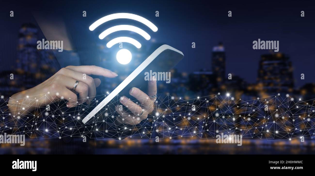 WLAN-Konzept. Weißes Tablet mit Touch-Bedienung und digitalem Hologramm-Wi-Fi-Schild auf dunklem, unscharfem Hintergrund der Stadt. Verbindung zum Business-Netzwerk Stockfoto