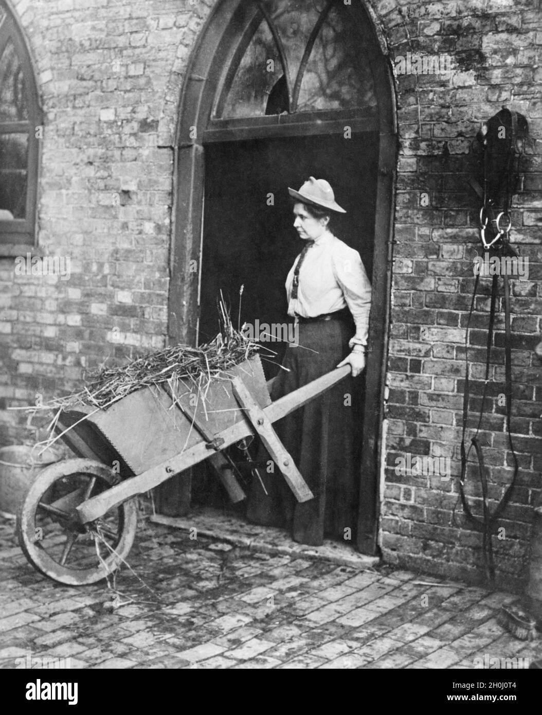 Frau auf einer englischen Farm, die einen Stall ausmuckt. (Undatierte Fotografie) [automatisierte Übersetzung] Stockfoto