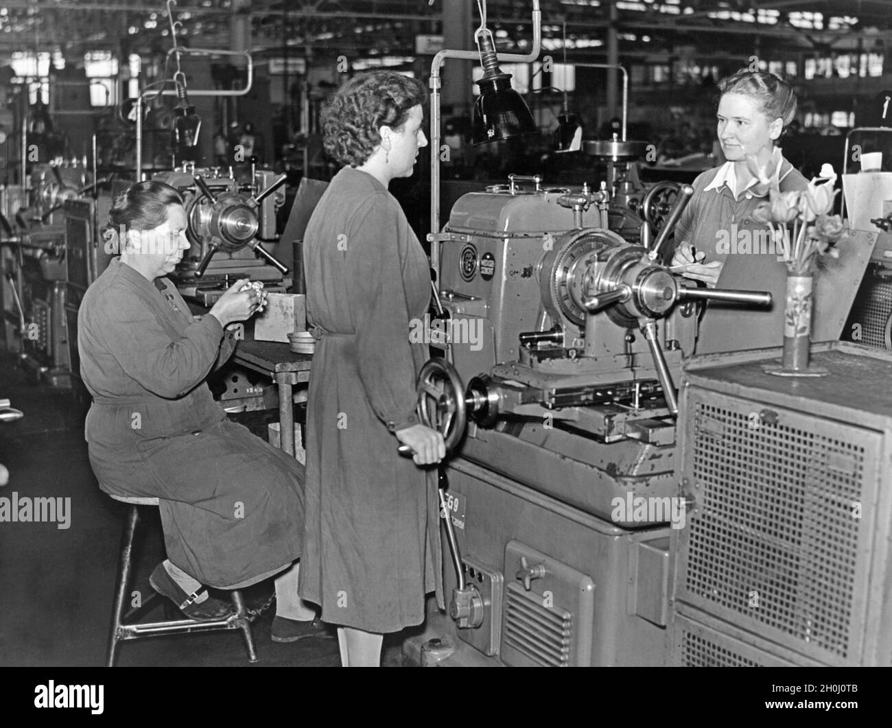 Während ihres täglichen Rundgangs durch den Workshop befragt die Sozialarbeiterin die Arbeiter nach ihren Wünschen und möglichen Verbesserungen an ihrem Arbeitsplatz. [Automatisierte Übersetzung] Stockfoto