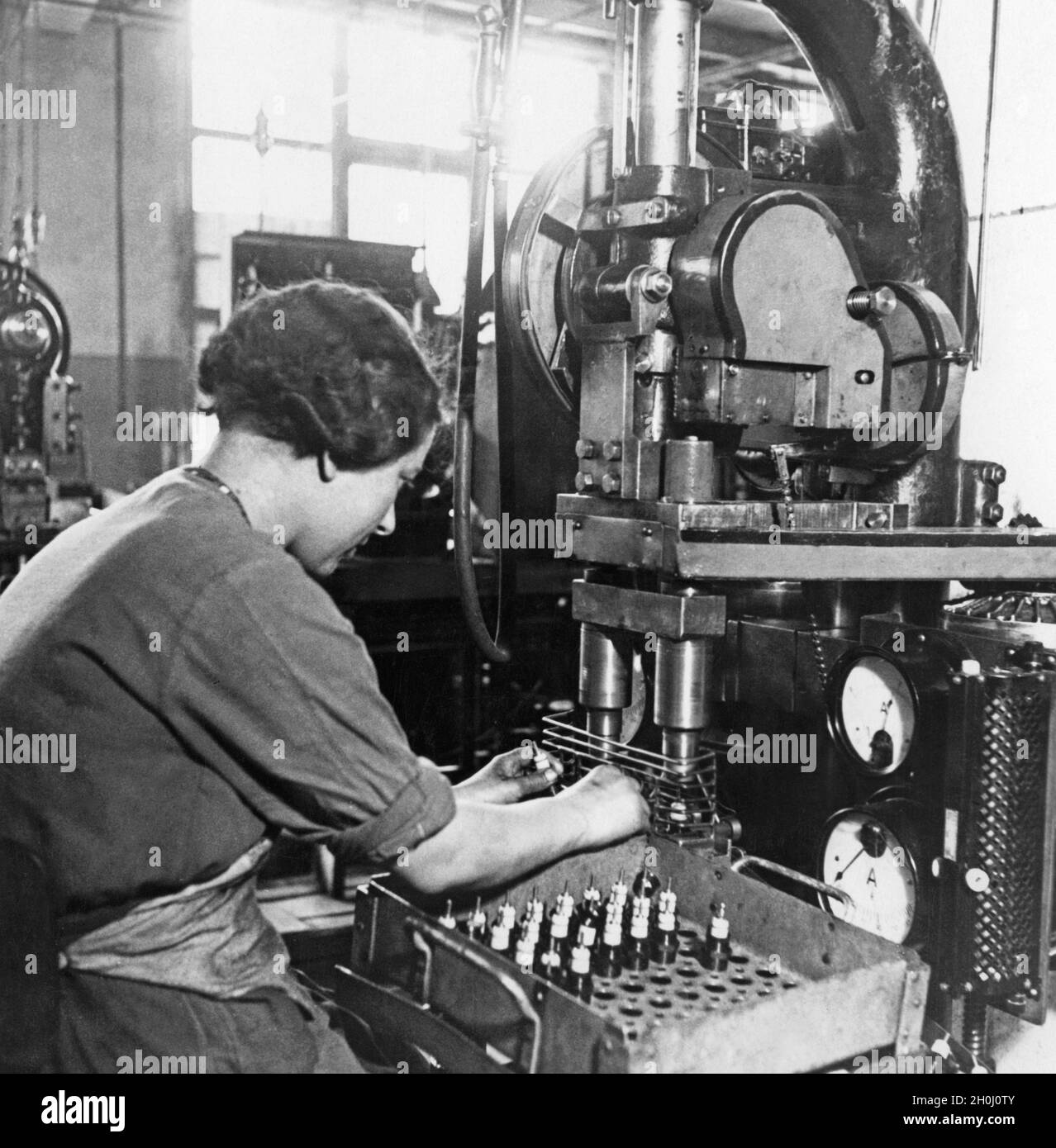 Bosch-Zündkerzenfabrik: Ein Arbeiter presst Isolatoren in das Zündkerzengehäuse. [Automatisierte Übersetzung] Stockfoto