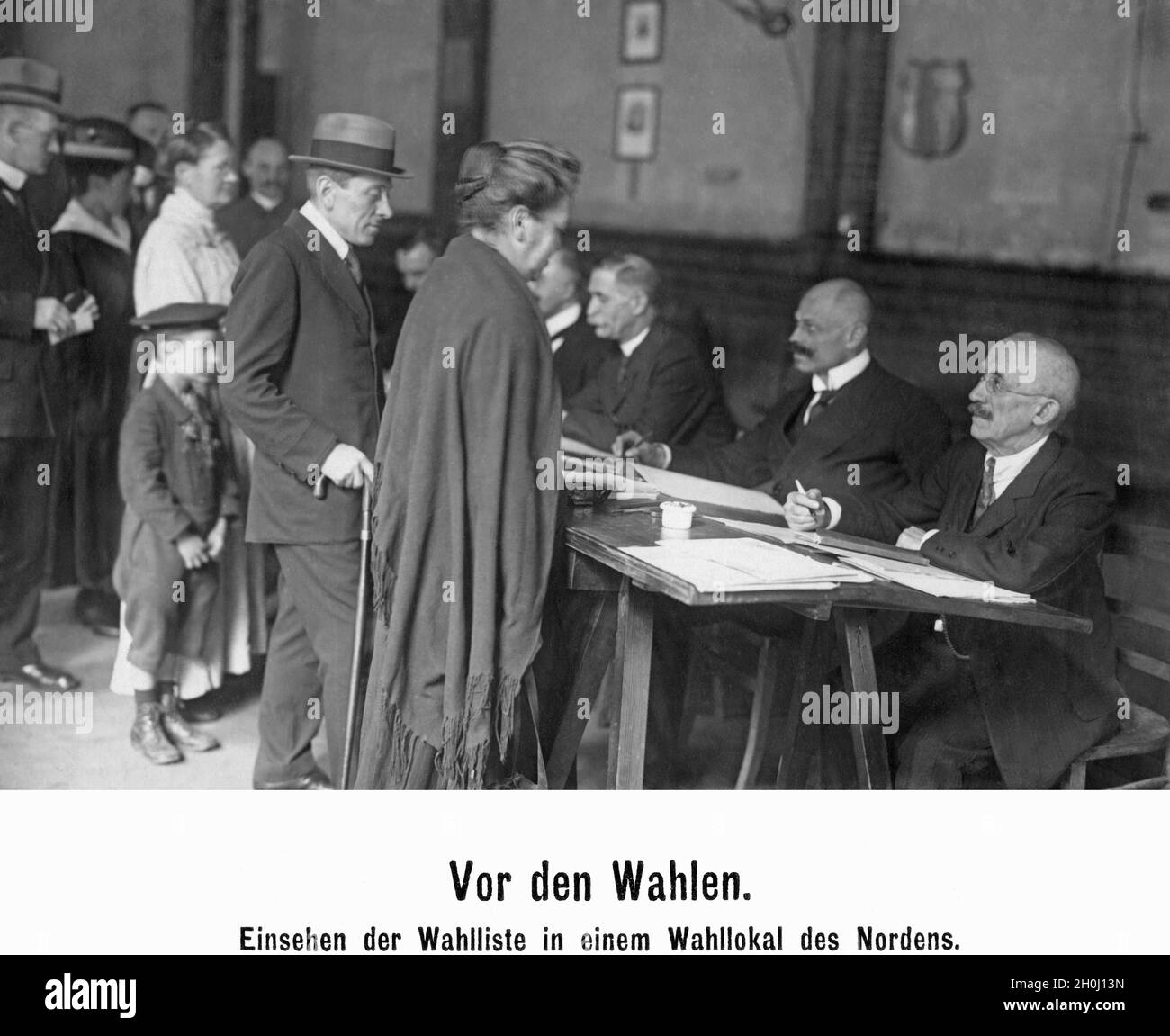 Vor der Wahl in die Weimarer Nationalversammlung am 19. Januar 1919 schauen die Wähler in einem Wahllokal in Norddeutschland auf die Wahlliste: Erstmals durften Frauen als gleichberechtigte Bürger wählen. [Automatisierte Übersetzung] Stockfoto