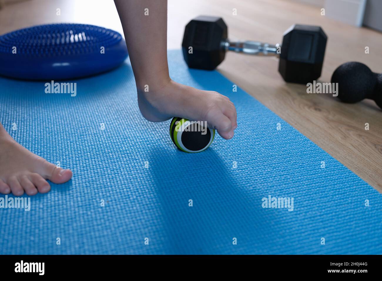 Der Kinderfuß ruht auf einem kleinen Gymnastikball, um die Füße aus der Nähe zu massieren Stockfoto
