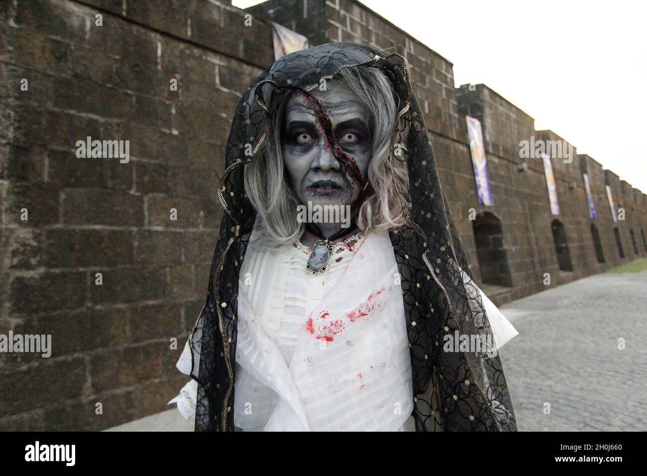 Eine Cosplayerin, die als gejagte Maria Clara verkleidet ist, eine bekannte Figur aus Noli me Tangere, einem Roman des Nationalhelden Jose Rizal, posiert während des Zombie Run-Events in Intramuros Manila, Philippinen, vor einer Kamera. Stockfoto