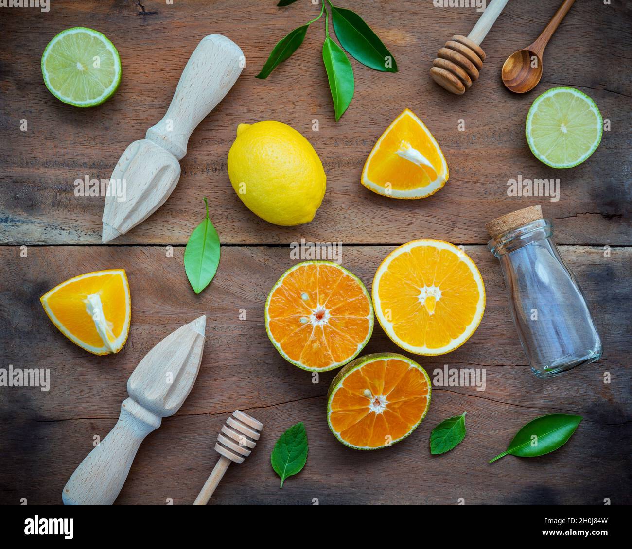 Gemischte frische Zitrusfrüchte und orange Blätter Hintergrund. Zutaten für Sommer Zitronensaft mit Entsafter und Glas Flasche. frische Zitronen, Limetten und Orang Stockfoto