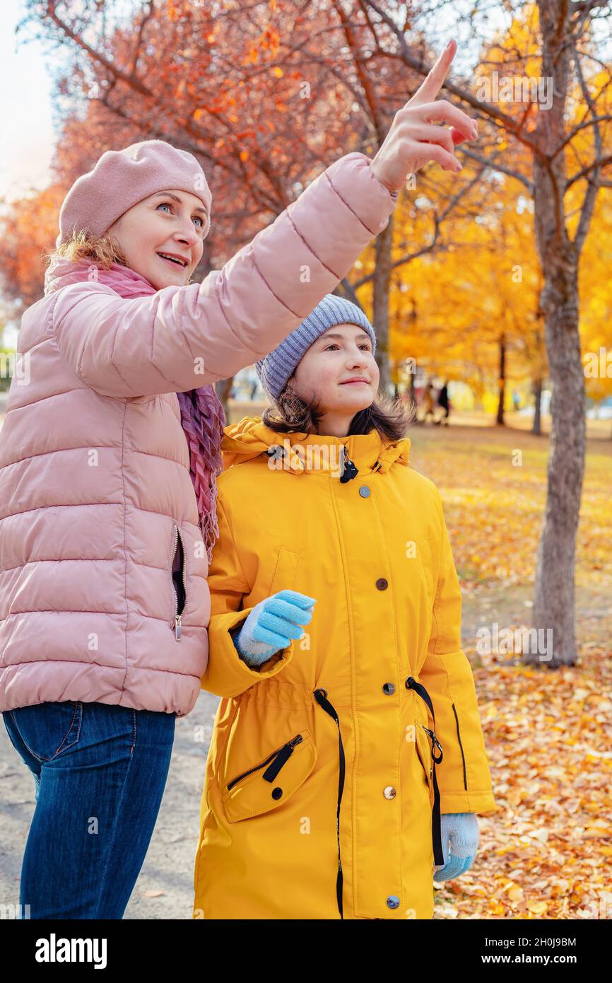 Positiv lächelnde kaukasische Mutter mit ihrer Tochter verbringen Zeit zusammen im Stadtpark. Vertikale Aufnahme. Herbststimmung. Herbst sonnigen Tag Hintergrund. Gesund Stockfoto
