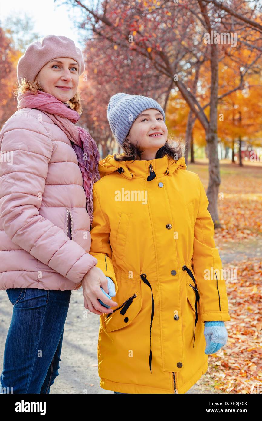 Positiv lächelnde kaukasische Mutter mit ihrer Tochter verbringen Zeit zusammen im Stadtpark. Vertikale Aufnahme. Herbststimmung. Herbst sonnigen Tag Hintergrund. Gesund Stockfoto