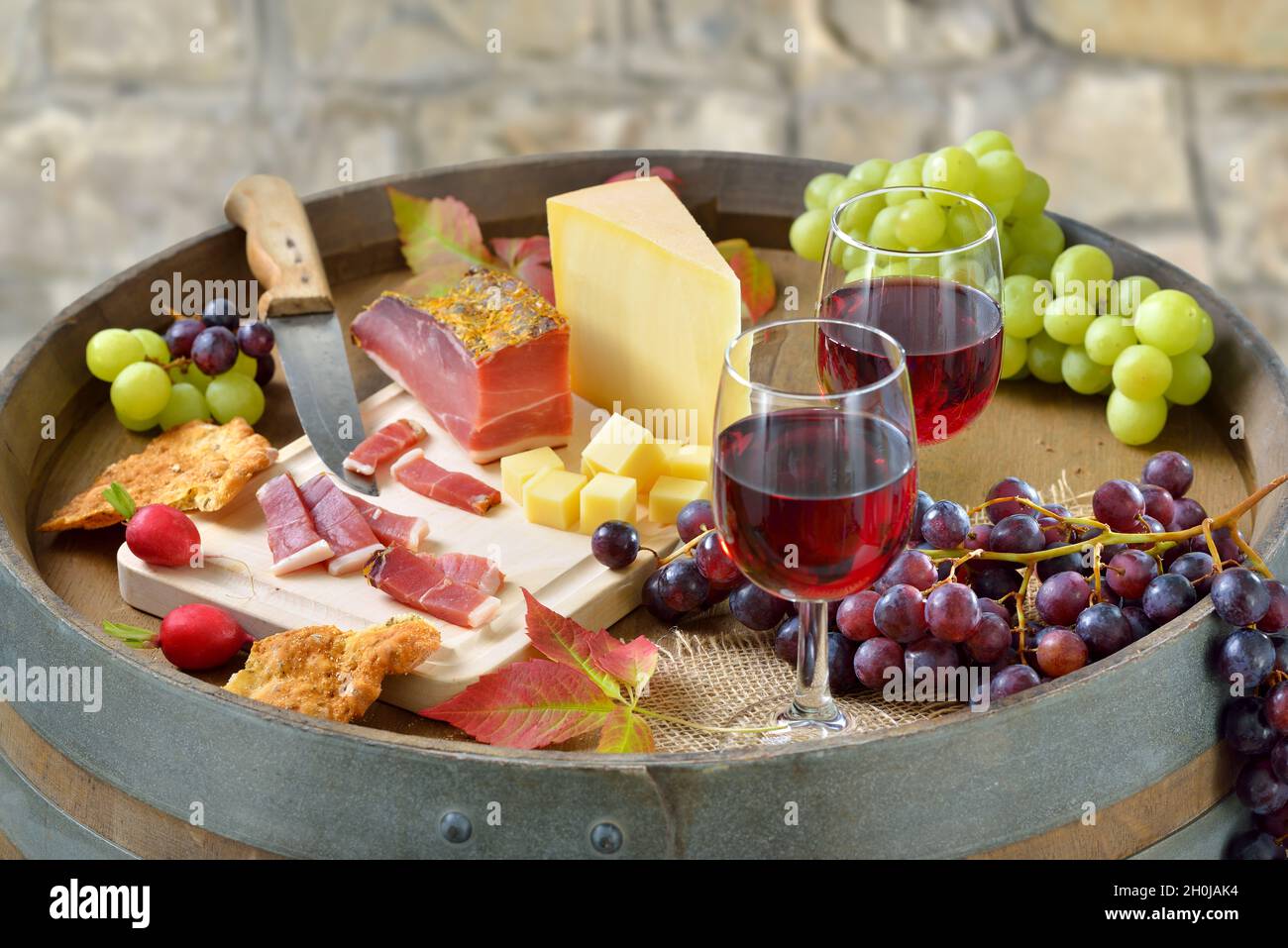 Herzhafte Südtiroler Jause mit geräuchertem Speck, leckerem Bergkäse, knusprigem Roggenbrot und einem guten lokalen Rotwein Stockfoto