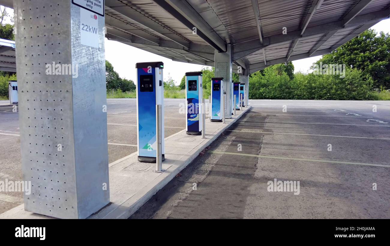 Nahaufnahme einer elektrischen Ladestation mit mehreren blauen Ladegeräten und einem leeren Parkplatz Stockfoto