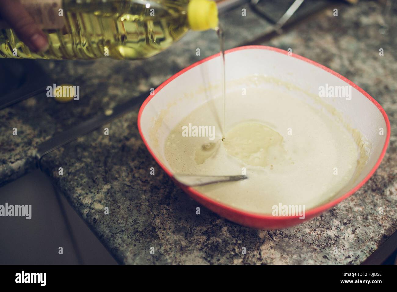 Pfannkuchen kochen - den Rest der Milch hinzufügen und schlagen - der Teig sollte mäßig flüssig sein Stockfoto