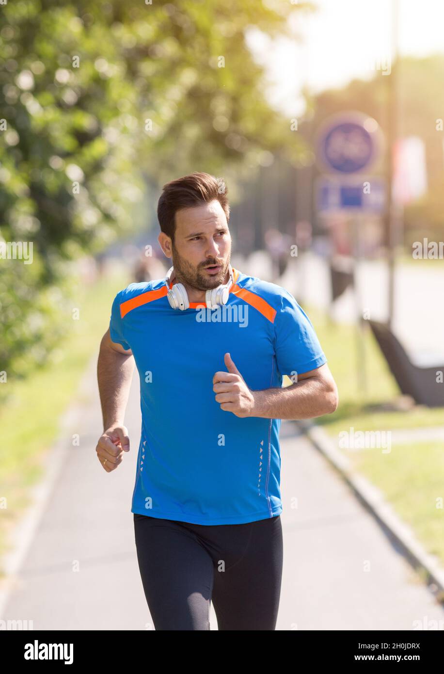 Zufriedener, gutaussehender Mann, der im Park läuft. Joggen am Morgen in der Stadt Stockfoto