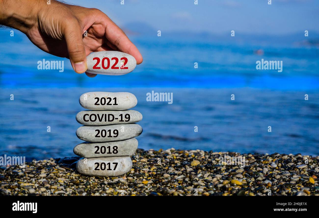 Frohes neues Jahr 2022 steht vor dem Konzept. Mann, der Stein zum Kiesturm hinzufügt, weil das neue Jahr 2022 das Jahr 2021 ersetzt. Schönes konzeptionelles Foto. Stockfoto
