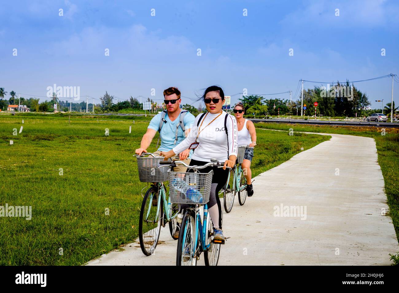 Drei Fahrradfahrer fahren durch die Reisfelder in Hoi an. Stockfoto