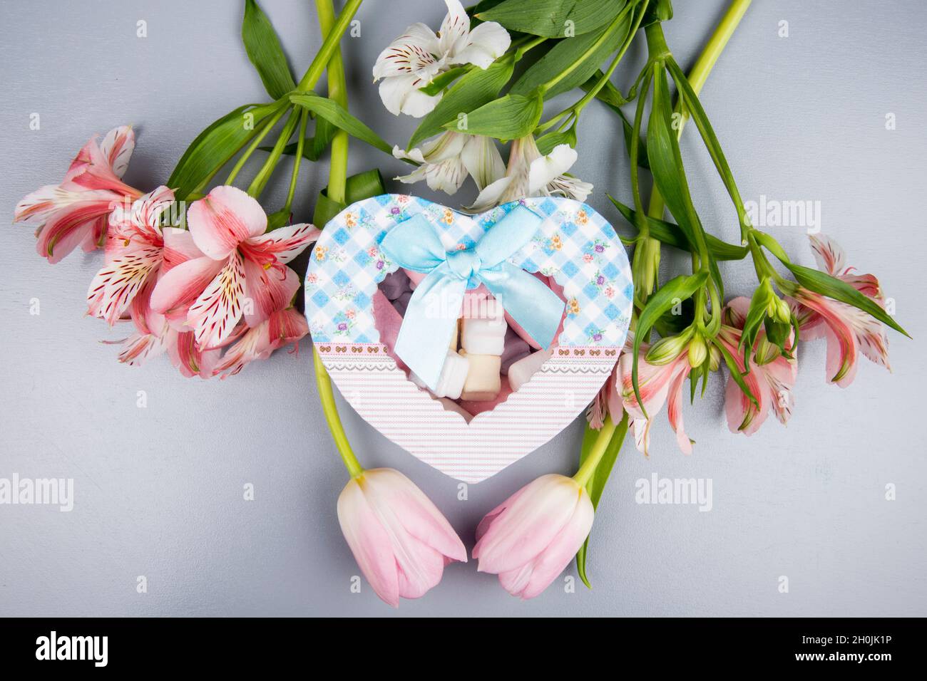 Draufsicht auf eine herzförmige Geschenk-Box mit marmelow und rosa und weißen Farbe Alstroemeria und Tulpen-Blumen auf weißem Hintergrund Stockfoto