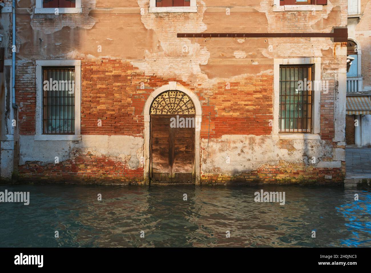 Antikes Gebäude außen mit Eingangstür vom Wasserkanal in Venedig, Italien Stockfoto