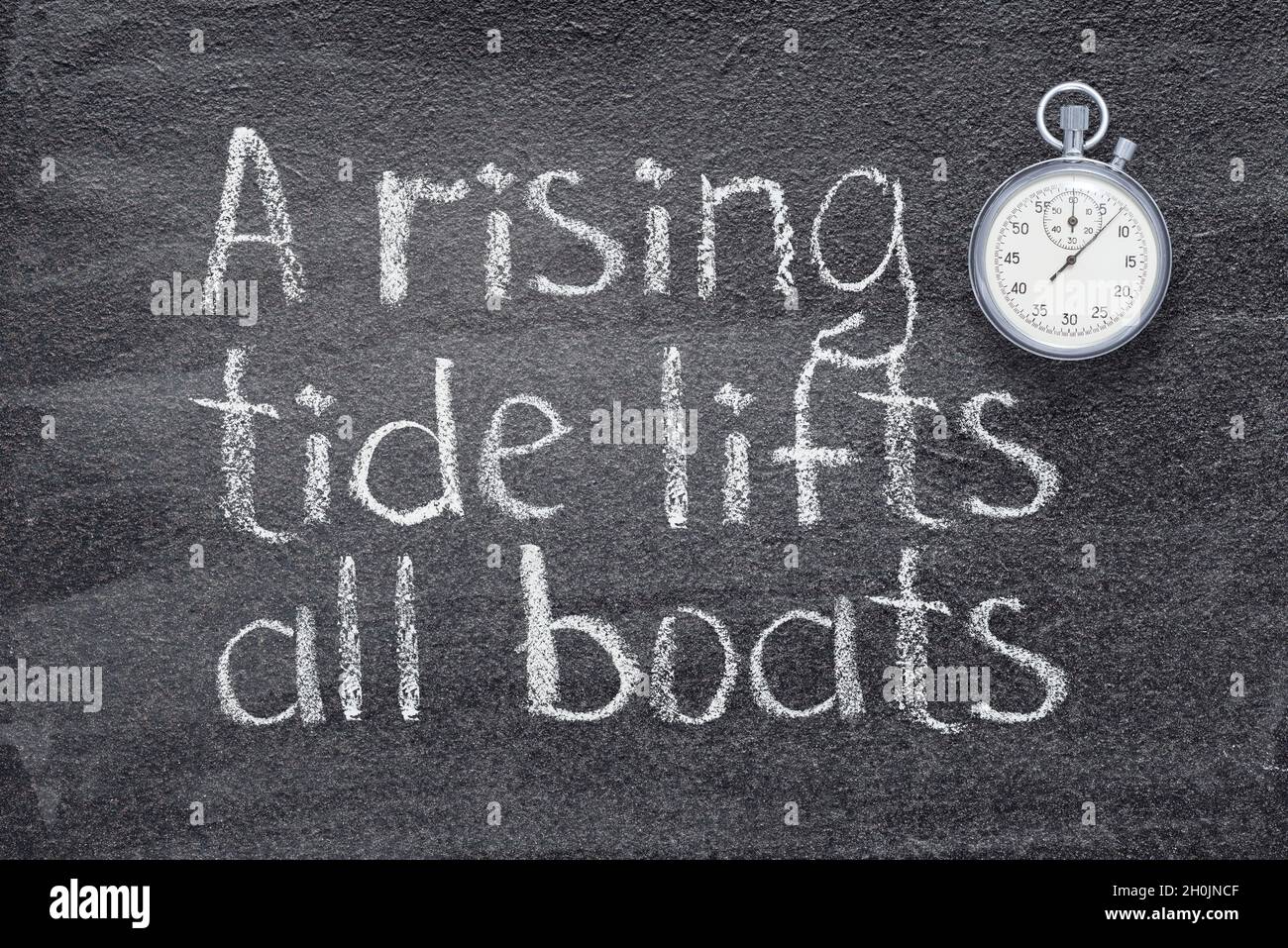 Eine steigende Flut hebt alle Boote Sprichwort geschrieben auf Kreidetafel mit vintage präzise Stoppuhr Stockfoto