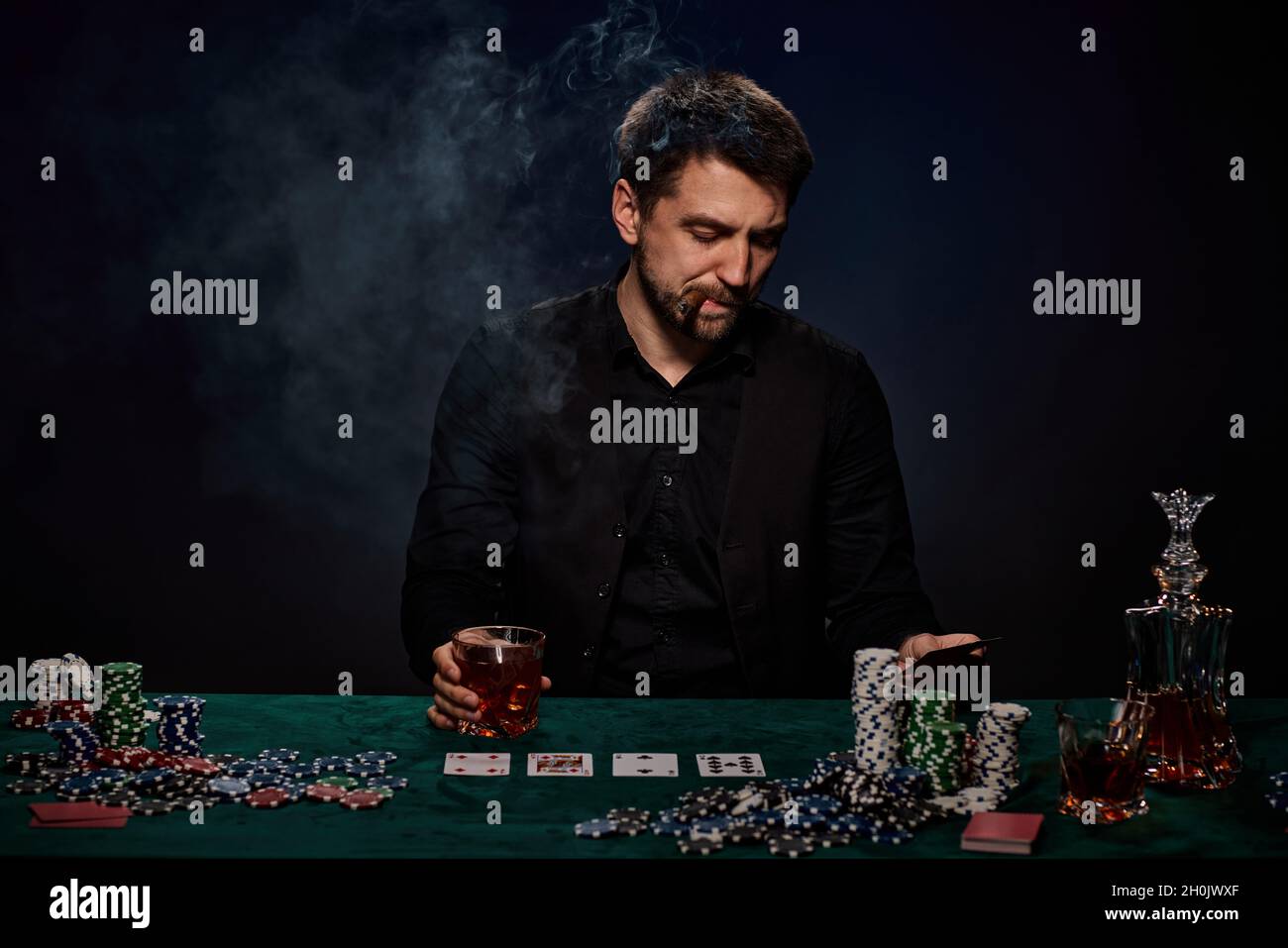 Bärtiger Casino Spieler Mann, der Poker auf dem grünen Tisch spielt Stockfoto