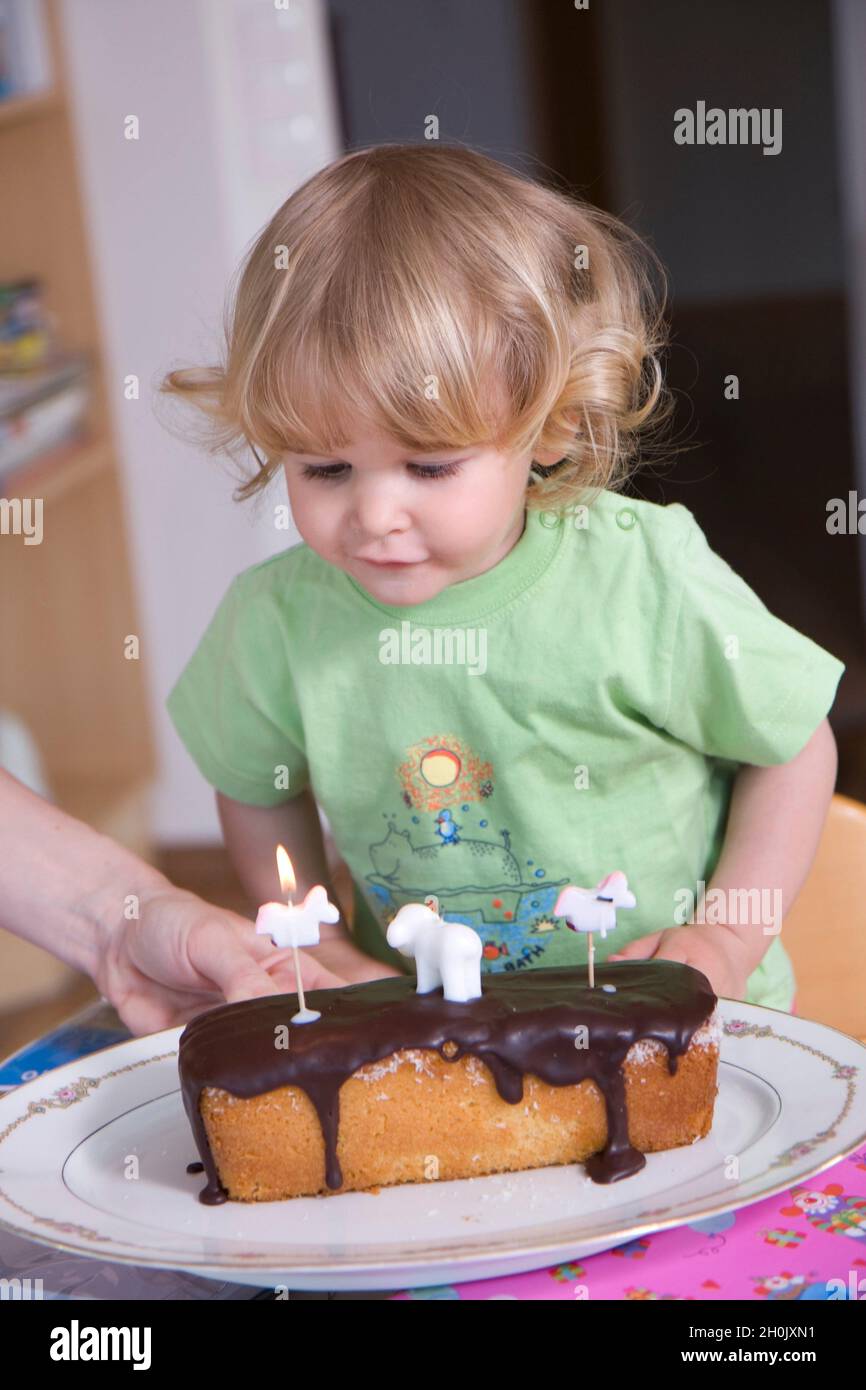 Kleines Mädchen, das eine Kerze auf einem Geburtstagskuchen ausbläst Stockfoto
