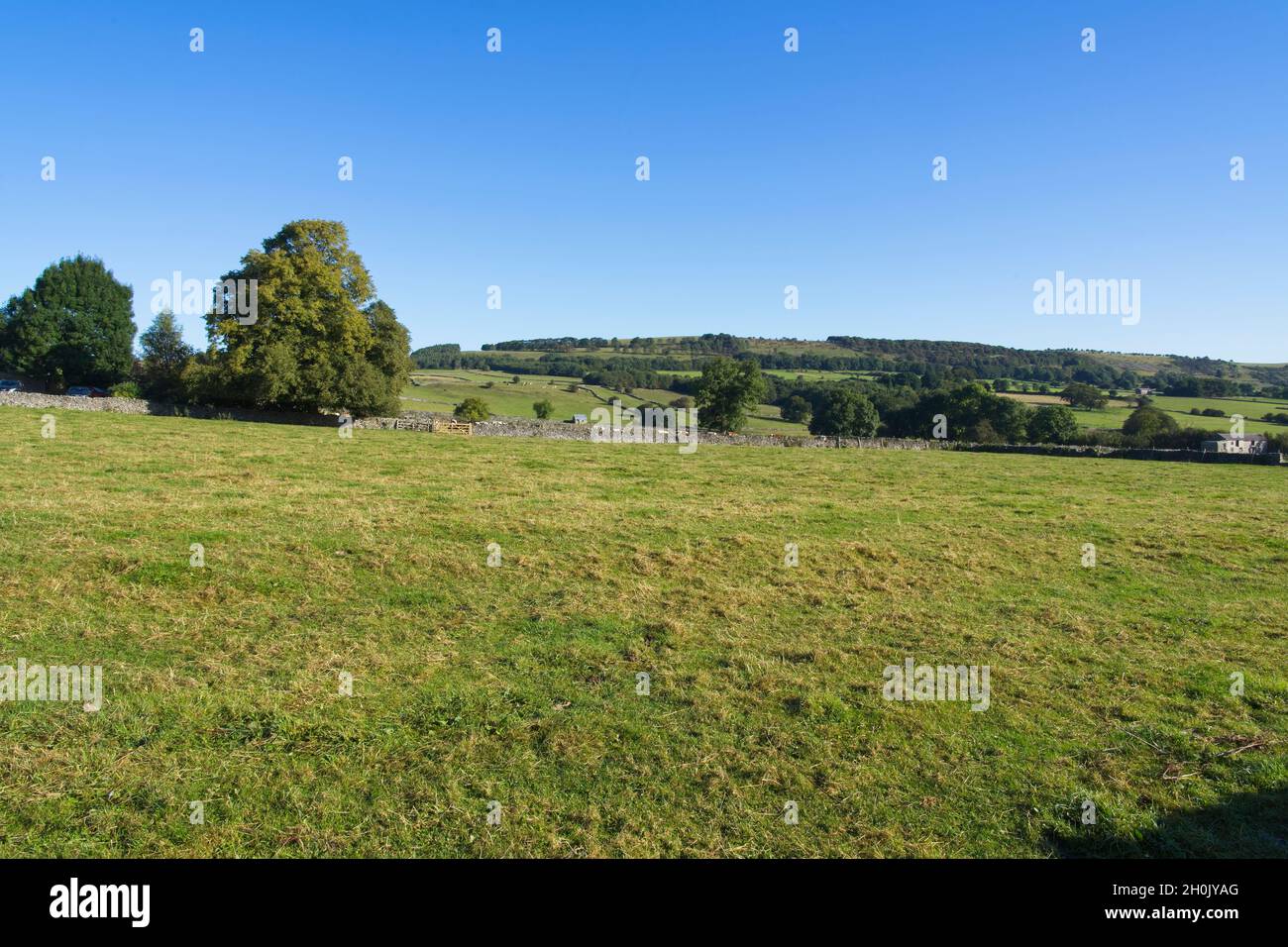 Blauer Himmel über dem von Bäumen gesäumten Derbyshire Peak District in der Nähe von Monsal Head Stockfoto