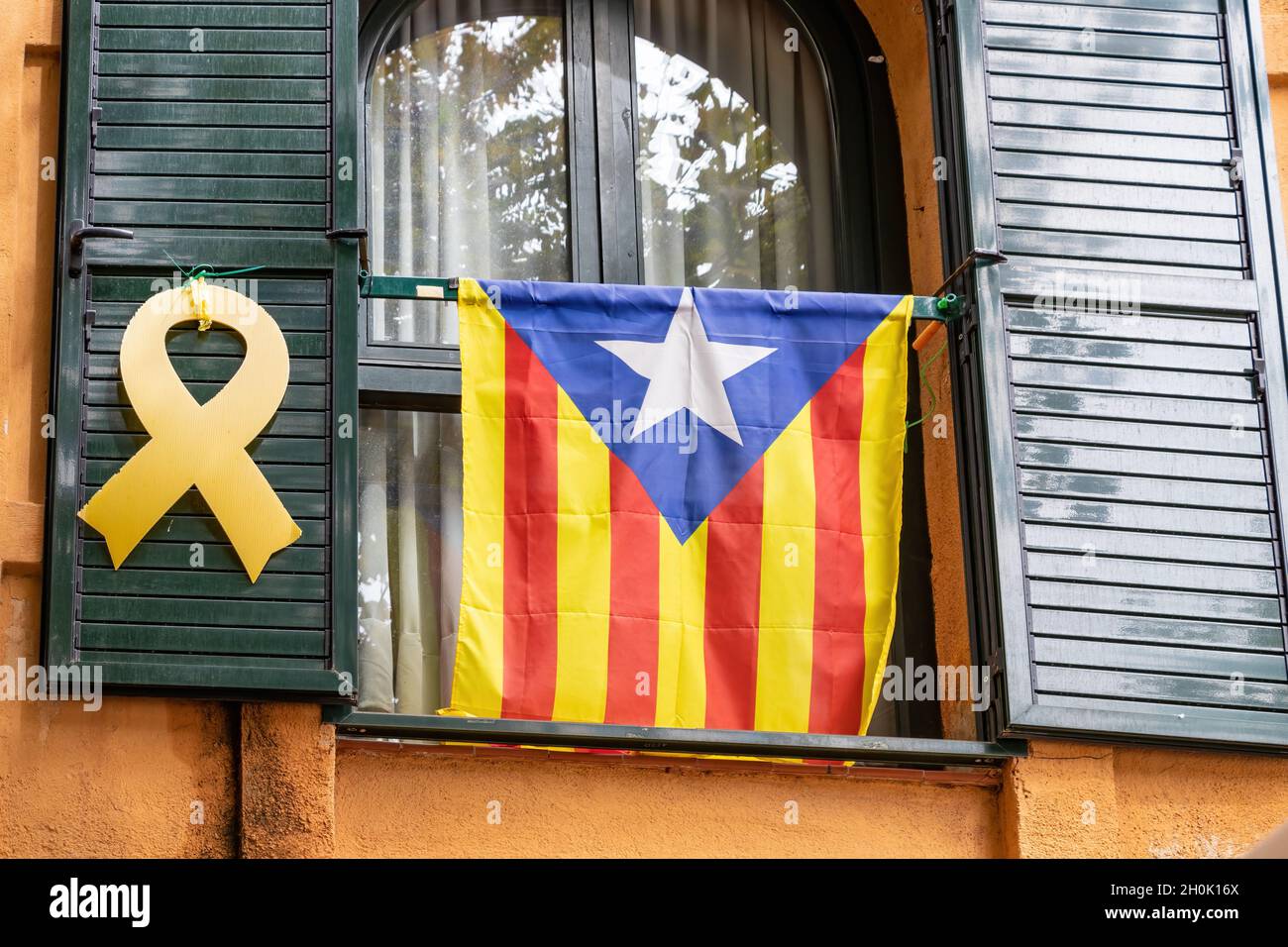 Katalanische Unabhängigkeitsfahne und gelbes Band, das an einem Fenster hängt, fordern die Unabhängigkeit Kataloniens und die Freiheit des inhaftierten Politikers Stockfoto