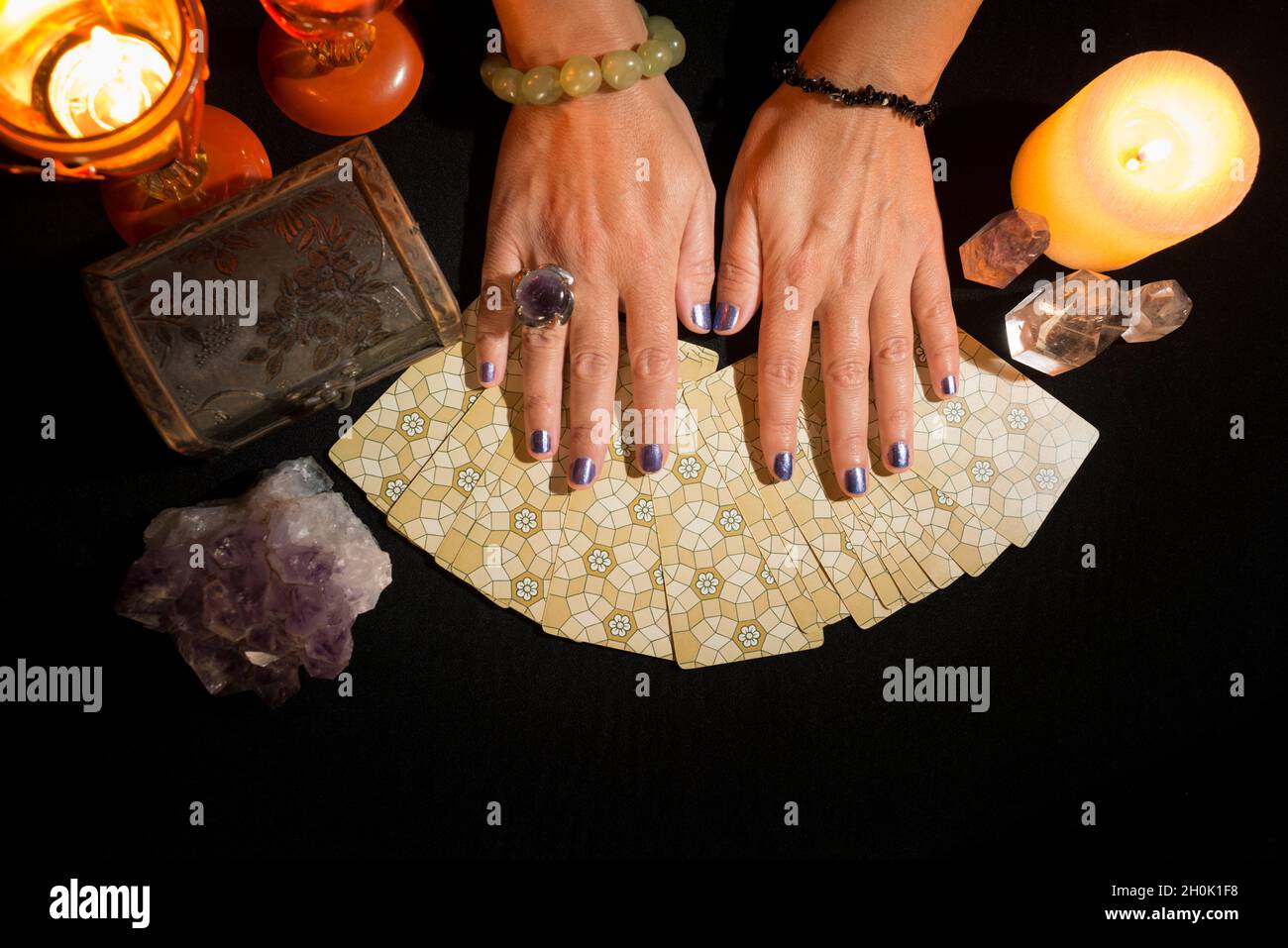 Detail der Hände einer Frau auf Tarot-Karten auf einem schwarzen Kartentisch. Konzept einer Wahrsagerei mit Tarot-Karten. Stockfoto