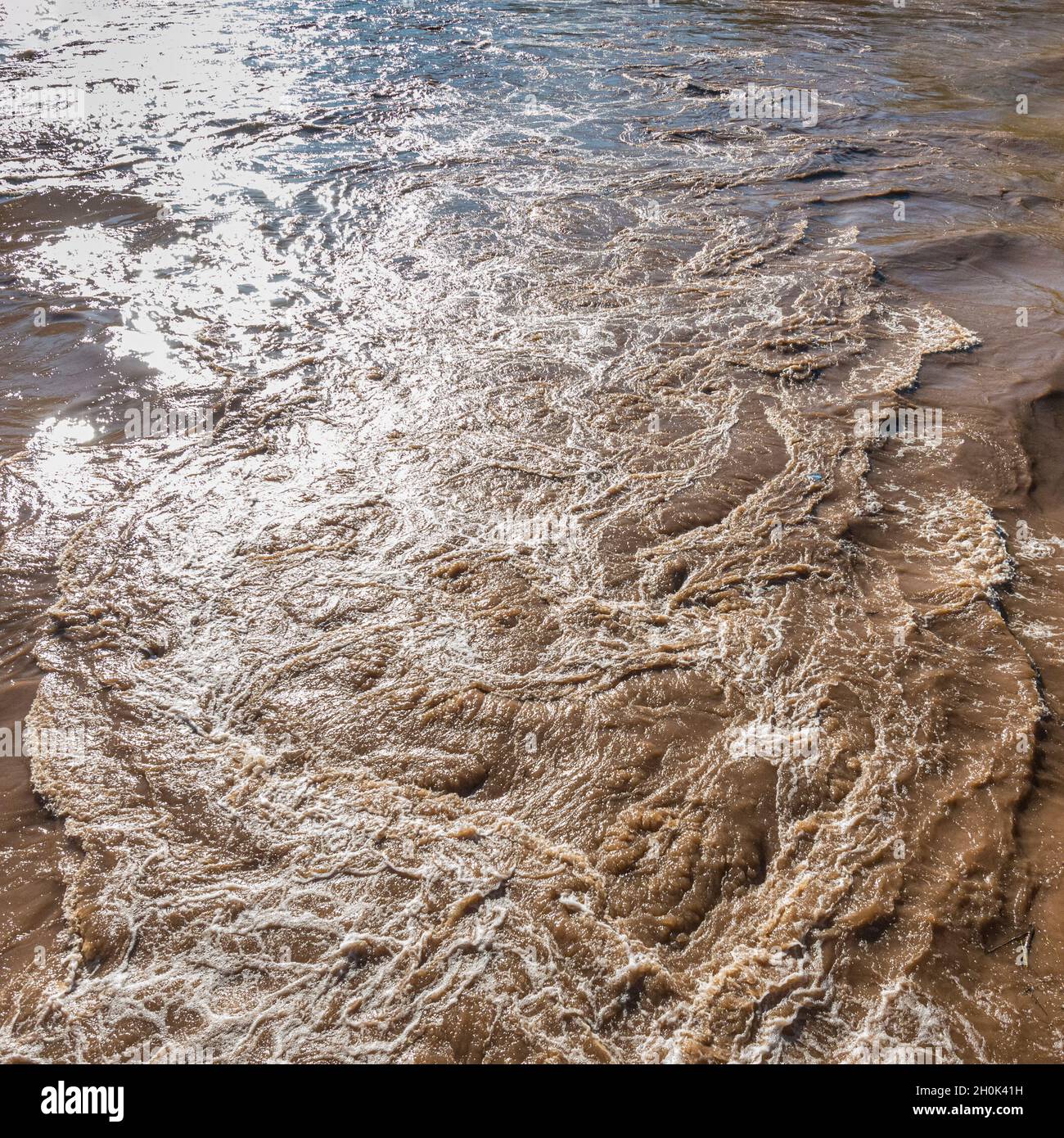 Künstlerische Sicht auf turbulentes schlammiges Flußwasser Stockfoto