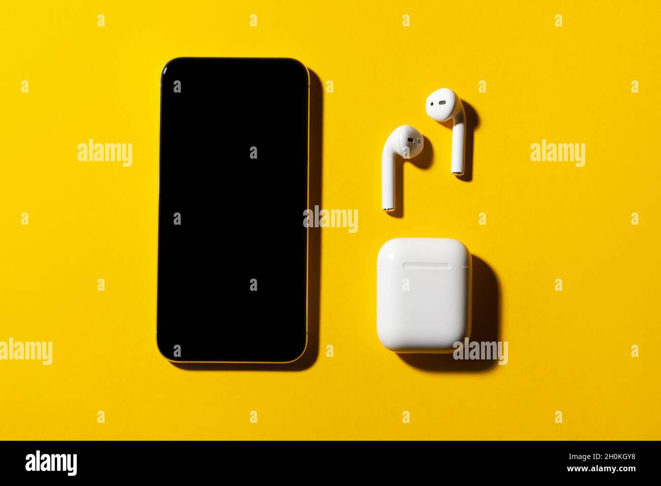 Smartphone und kabellose Kopfhörer auf gelbem Hintergrund. Stockfoto