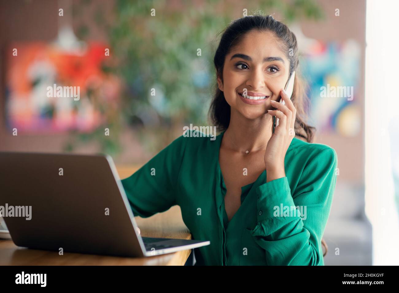 Schöne arabische Frau, die online arbeitet, Telefongespräche führt, Speicherplatz kopiert Stockfoto