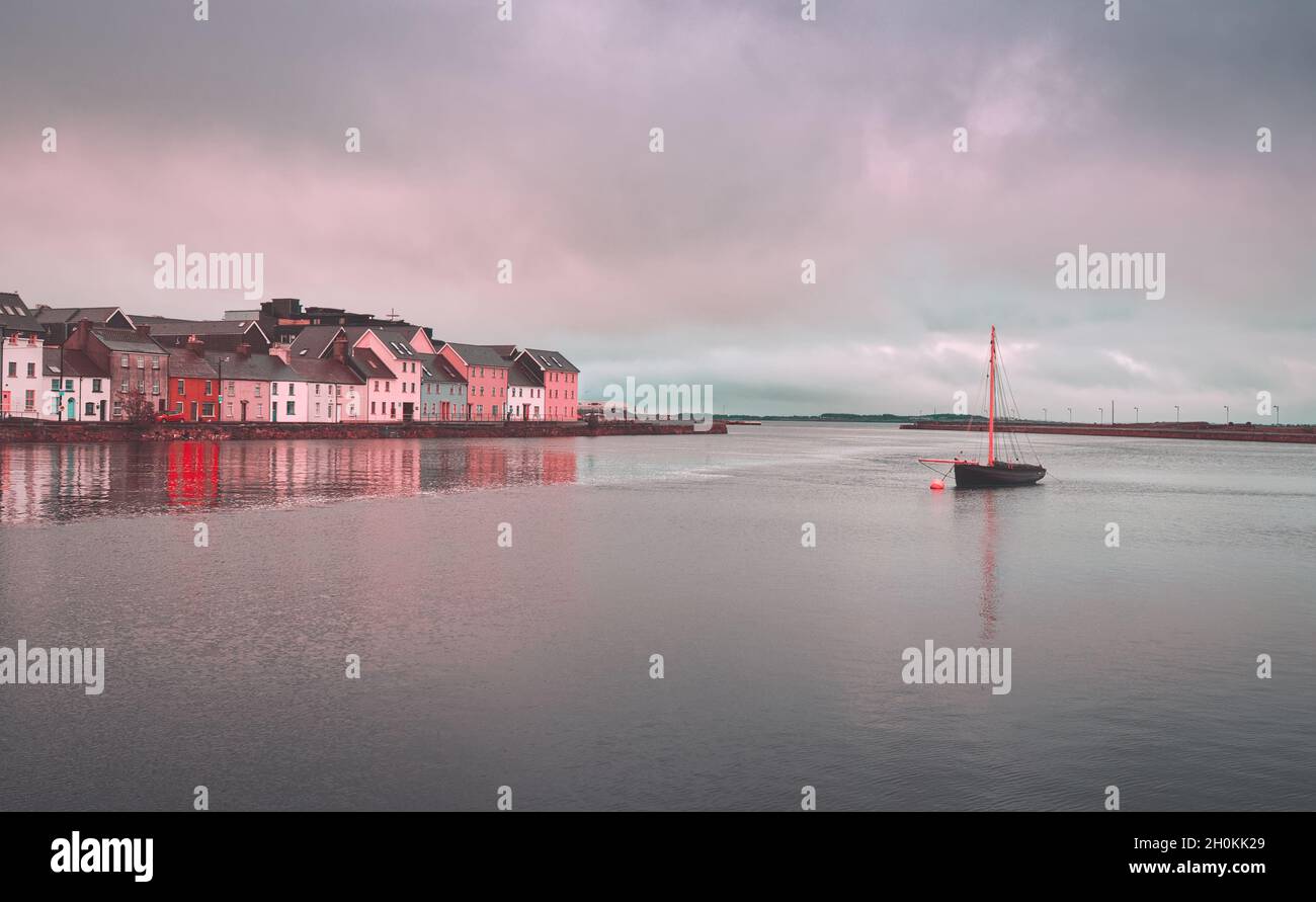 Wunderschöne Stadtlandschaft mit altem hölzernen Fischerboot namens Galway Hooker im Corrib River bei den bunten Häusern in Galway City, Irland Stockfoto