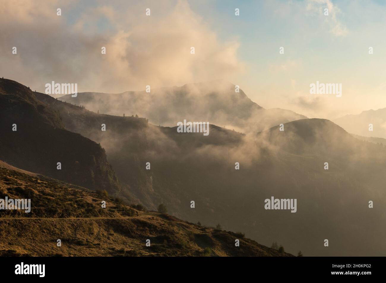 Herbst auf den Alpen in Italien, die Landschaft der Wälder und Berge mit farbigen Laub. Nebel und Wolken rund um den Berg. Stockfoto