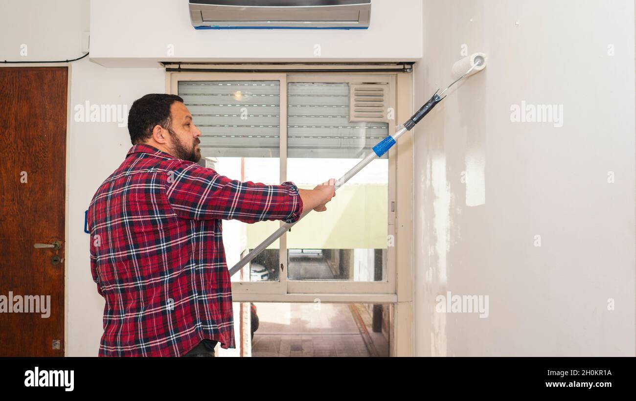 Mann mittleren Alters malte eine Wand seiner Wohnung Stockfoto