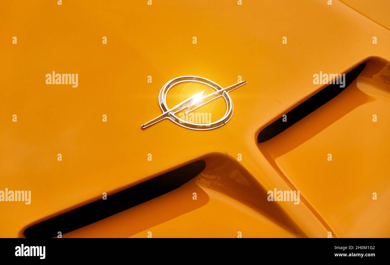 Opel-Logo aus einem stilisierten silbernen Blitz im Kreis auf der Motorhaube eines orangefarbenen Opel GT-Sportwagens in Lehnin, Deutschland, 12. September 2021. Stockfoto