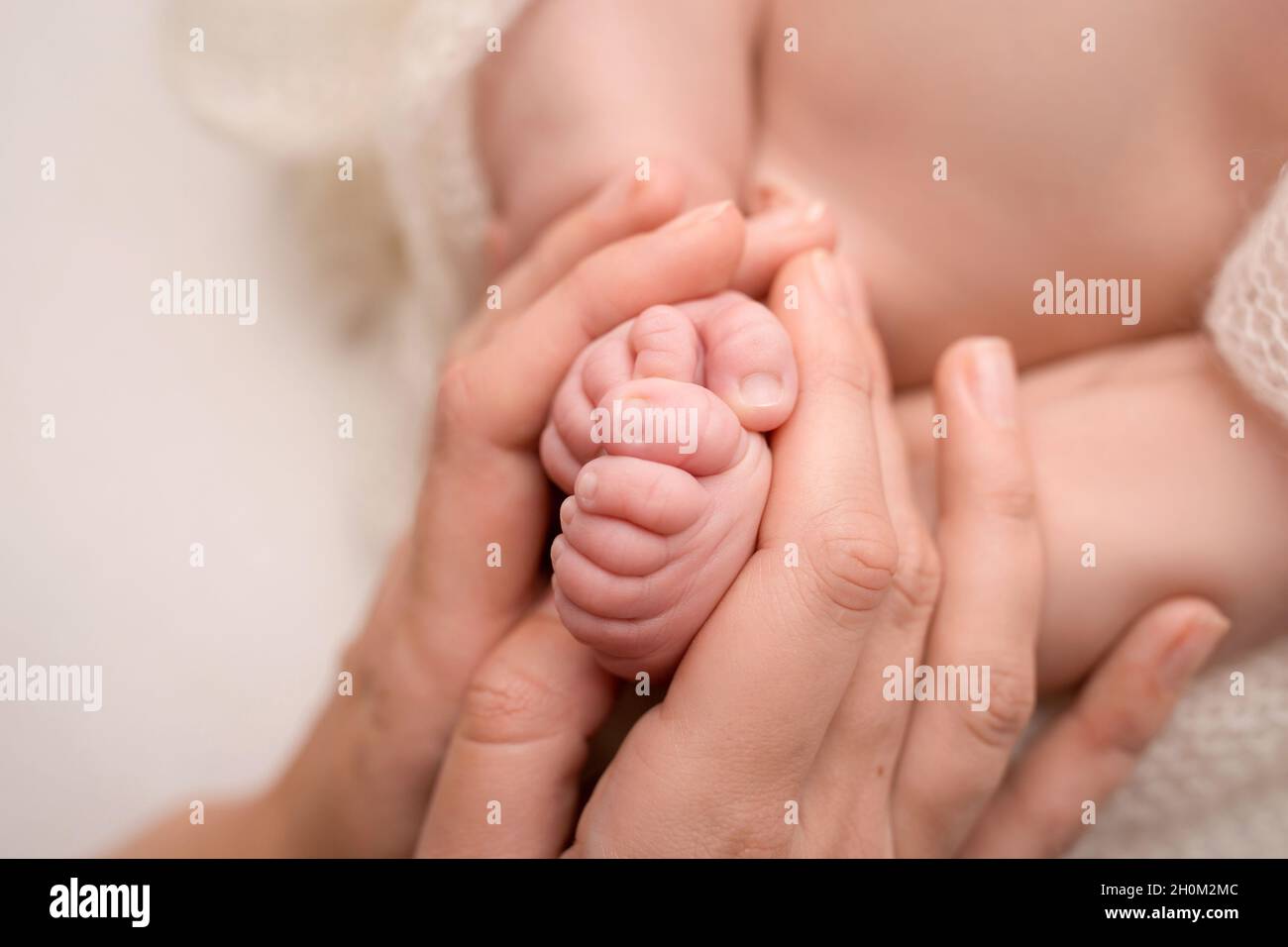 Liebevolle Mutter halte die Beine des Babys. Frohe Kindheit. Elterliche Betreuung. Konzept einer glücklichen Familie. Stockfoto