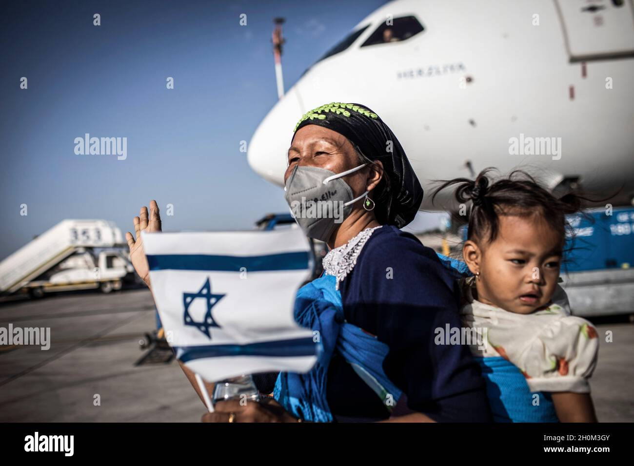 Tel Aviv, Israel. Oktober 2021. Neue jüdische Emigranten aus der indischen Gemeinschaft Bnei Menashe (Söhne Manasses) halten israelische Fahnen, als sie bei der Ankunft am Ben Gurion Airport in der Nähe von Tel aviv jubeln. 250 Emigranten der Bnei Menashe-Gemeinde, die angeblich zu den zehn verlorenen Stämmen Israels gehören, die sich in Indien niederließen, sind heute im Rahmen einer Operation des Ministers für Aliyah und Integration (Immigrantenabsorption) in Israel angekommen. Quelle: Ilia Yefimovich/dpa/Alamy Live News Stockfoto