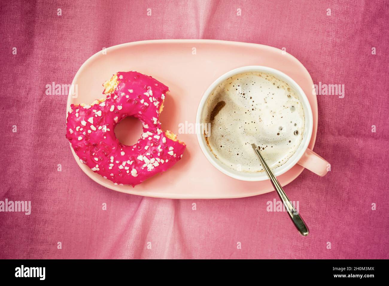 Leuchtend rosa gebitzte Krapfen in Teller und Kaffee, Draufsicht. Lebensmittelkonzept Stockfoto